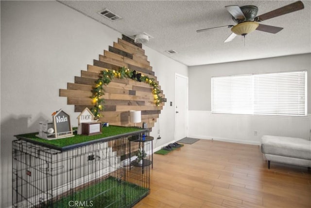 interior space featuring ceiling fan, a textured ceiling, and hardwood / wood-style floors