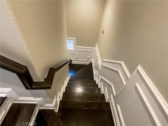 stairs featuring a wainscoted wall, hardwood / wood-style floors, and a decorative wall