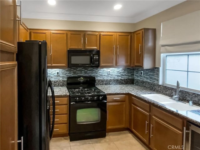 kitchen with a sink, decorative backsplash, black appliances, crown molding, and brown cabinets