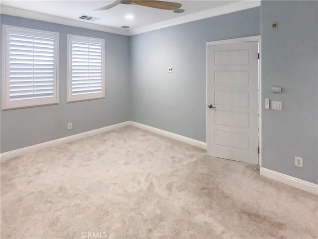 carpeted empty room with ornamental molding, a ceiling fan, visible vents, and baseboards