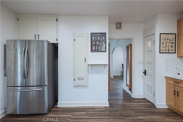 kitchen with dark wood-type flooring, white cabinetry, backsplash, and stainless steel fridge