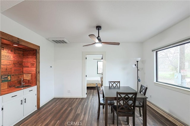 dining area with dark wood-type flooring, sink, and ceiling fan