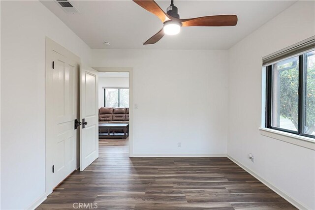 spare room with ceiling fan, a wealth of natural light, and dark hardwood / wood-style floors