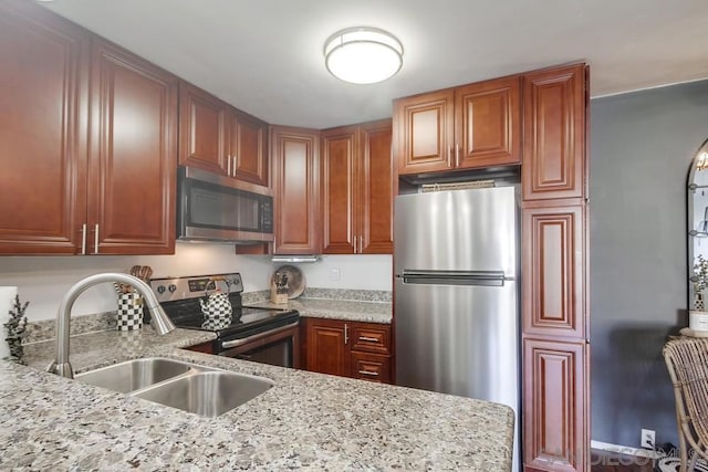 kitchen with stainless steel appliances, light stone counters, and sink