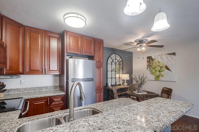 kitchen with light stone counters, sink, pendant lighting, and appliances with stainless steel finishes