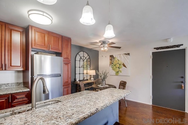 kitchen featuring decorative light fixtures, sink, dark hardwood / wood-style floors, stainless steel refrigerator, and ceiling fan