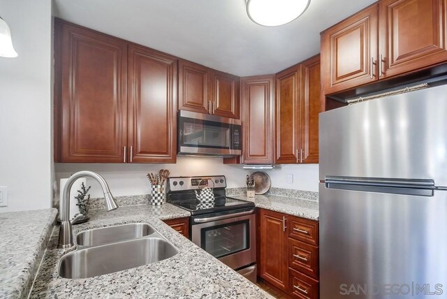 kitchen with light stone countertops, sink, and stainless steel appliances