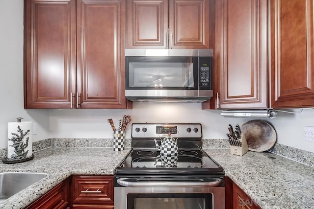 kitchen featuring light stone counters, sink, and appliances with stainless steel finishes