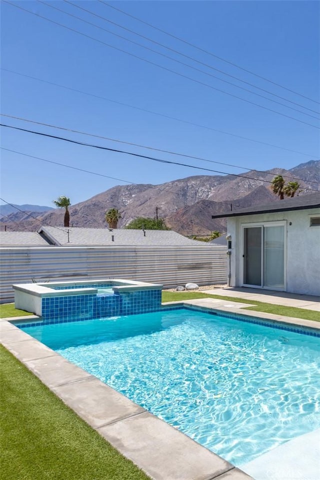 view of swimming pool with a mountain view and an in ground hot tub