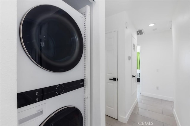 clothes washing area featuring stacked washer / drying machine and light tile patterned floors