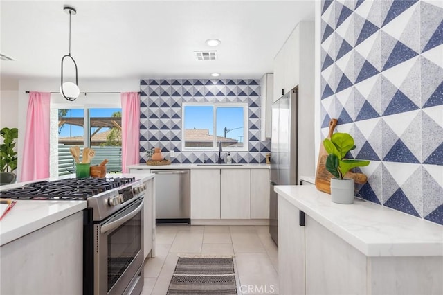 kitchen featuring light tile patterned floors, appliances with stainless steel finishes, white cabinets, and decorative light fixtures