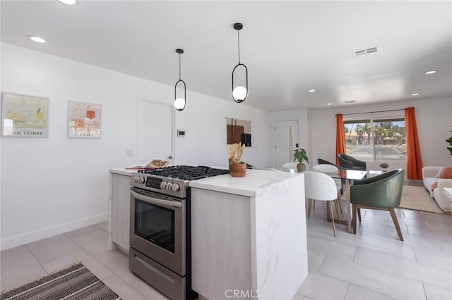 kitchen with light tile patterned floors, stainless steel range with gas cooktop, a kitchen island, and pendant lighting