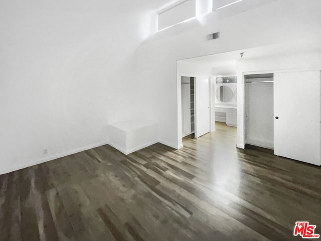 unfurnished bedroom featuring ensuite bath and dark hardwood / wood-style floors