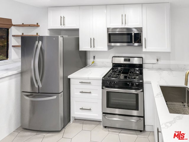 kitchen featuring white cabinetry, stainless steel appliances, sink, light stone counters, and light tile patterned floors