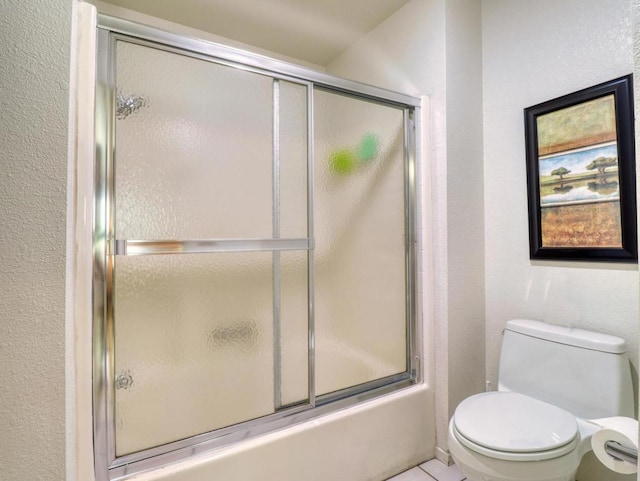 bathroom with toilet, tile patterned flooring, and shower / bath combination with glass door