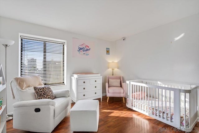 bedroom with dark wood-type flooring and a crib