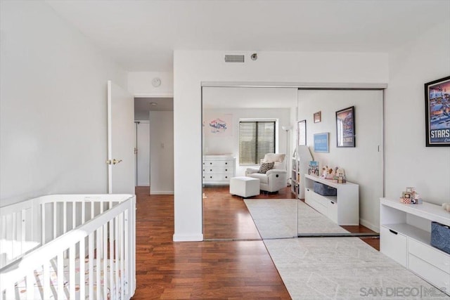 bedroom featuring a closet, dark hardwood / wood-style flooring, and a nursery area