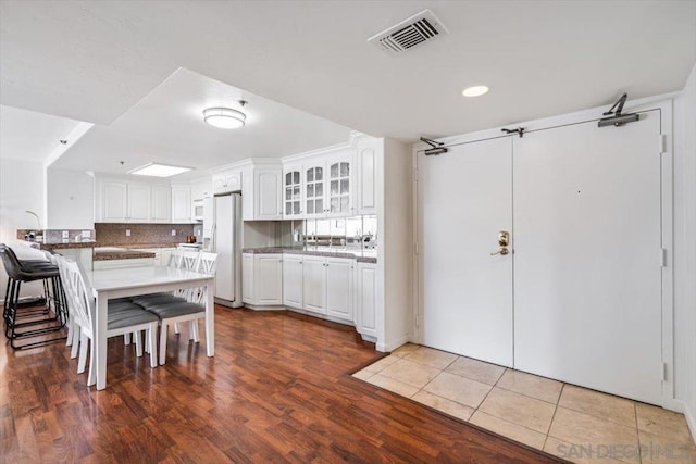 kitchen featuring backsplash, kitchen peninsula, white appliances, a breakfast bar area, and white cabinets