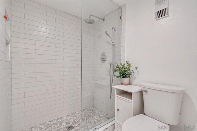 bathroom with toilet and a tile shower