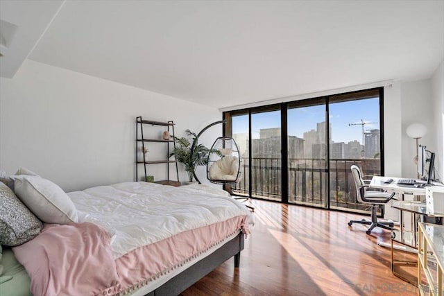 bedroom featuring hardwood / wood-style flooring, a wall of windows, and access to outside