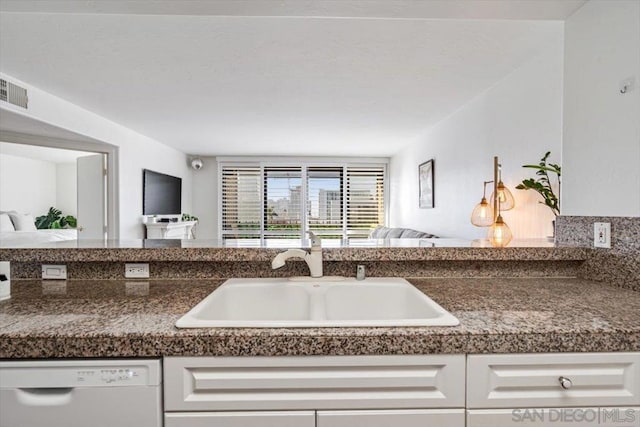 kitchen with white dishwasher, white cabinets, and sink