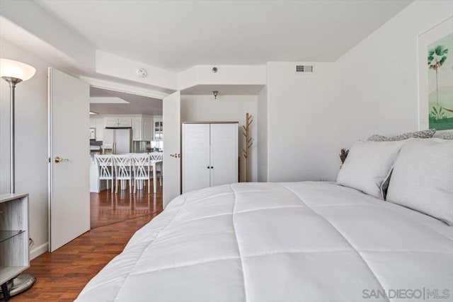 bedroom featuring white refrigerator with ice dispenser and dark hardwood / wood-style floors