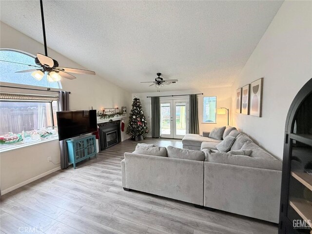 living room featuring light wood-type flooring, french doors, a textured ceiling, and vaulted ceiling