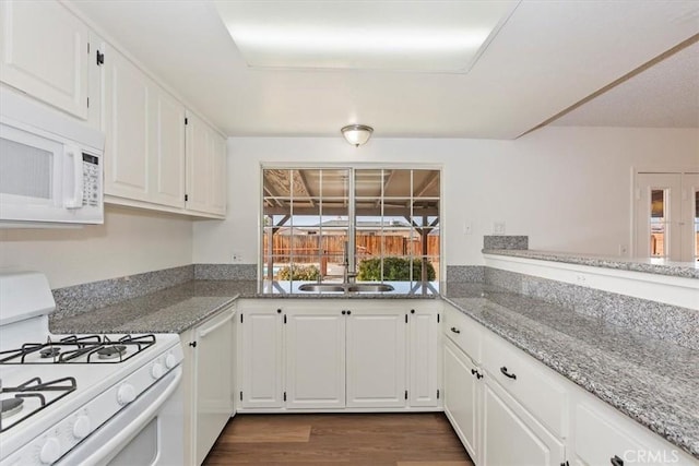 kitchen with sink, white cabinets, dark hardwood / wood-style flooring, light stone counters, and white appliances