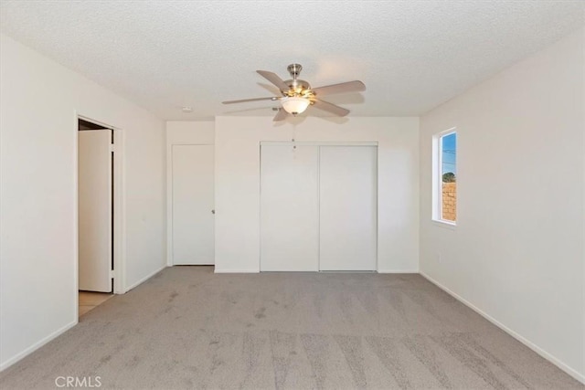 unfurnished bedroom featuring ceiling fan, light carpet, a closet, and a textured ceiling