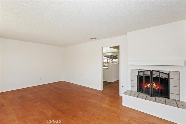 unfurnished living room featuring hardwood / wood-style floors, a textured ceiling, and a fireplace