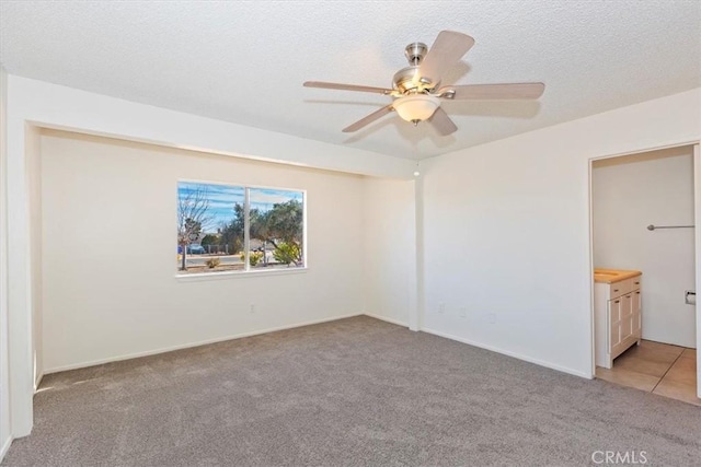 spare room with ceiling fan, light colored carpet, and a textured ceiling