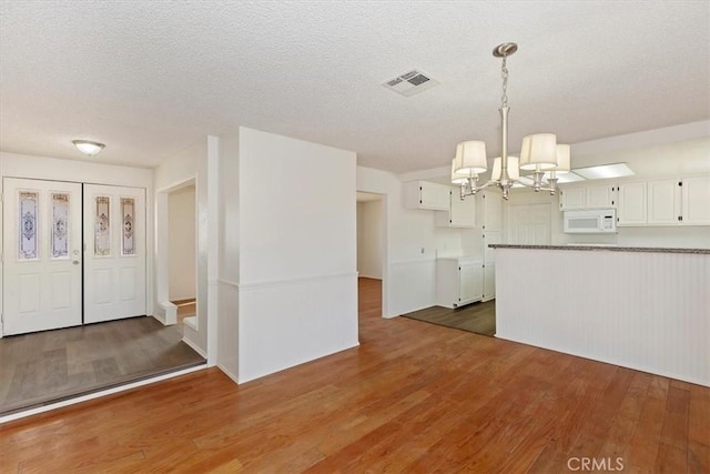 kitchen with hanging light fixtures, white cabinetry, and dark hardwood / wood-style flooring