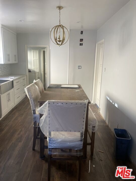 dining space featuring dark hardwood / wood-style flooring, a chandelier, and sink