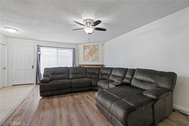 living room featuring ceiling fan, light wood-type flooring, and a textured ceiling