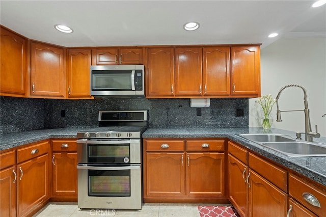 kitchen featuring appliances with stainless steel finishes, tasteful backsplash, light tile patterned flooring, ornamental molding, and sink