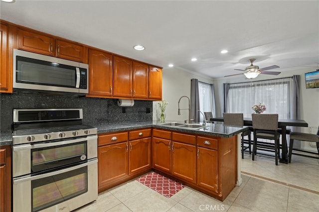 kitchen with backsplash, kitchen peninsula, sink, appliances with stainless steel finishes, and light tile patterned floors