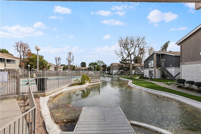 dock area featuring a water view and a fenced in pool