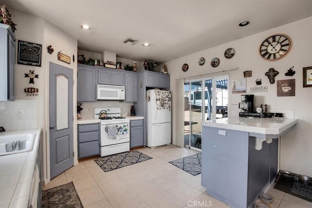 kitchen with white appliances, kitchen peninsula, tile countertops, and tasteful backsplash