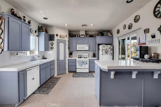 kitchen featuring white appliances, tile counters, a healthy amount of sunlight, sink, and light tile patterned floors