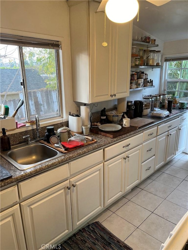 kitchen with white cabinets, light tile patterned floors, and vaulted ceiling