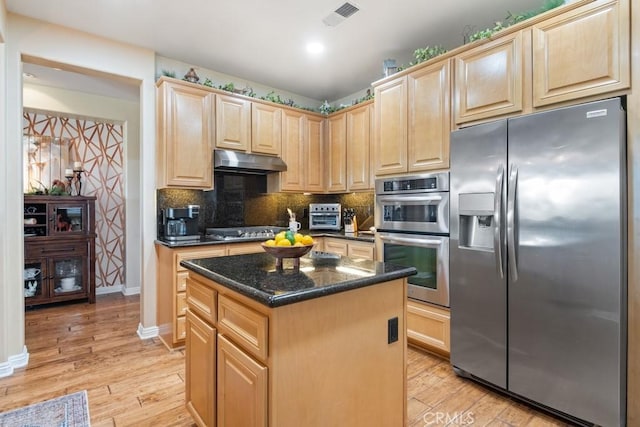 kitchen featuring light brown cabinetry, stainless steel appliances, dark stone countertops, a center island, and light hardwood / wood-style floors