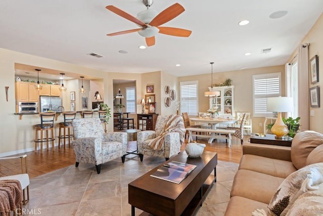 living room featuring ceiling fan, plenty of natural light, and light wood-type flooring