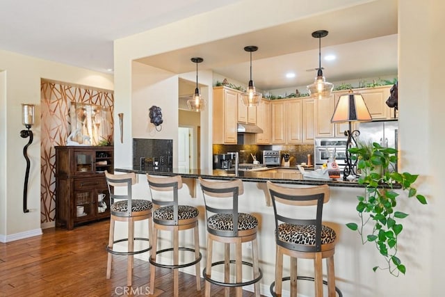 kitchen with tasteful backsplash, kitchen peninsula, oven, pendant lighting, and a breakfast bar area