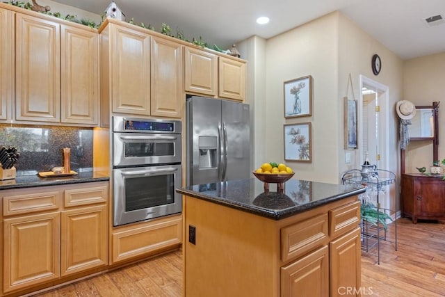 kitchen featuring decorative backsplash, appliances with stainless steel finishes, dark stone counters, light hardwood / wood-style flooring, and a kitchen island