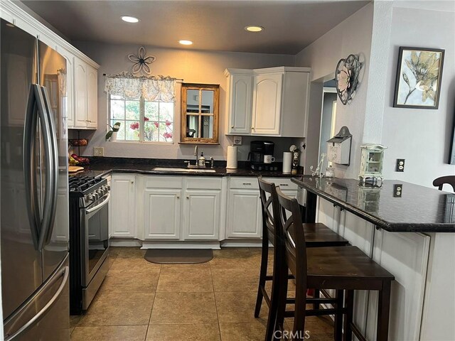 kitchen with kitchen peninsula, sink, a kitchen breakfast bar, stainless steel appliances, and white cabinets