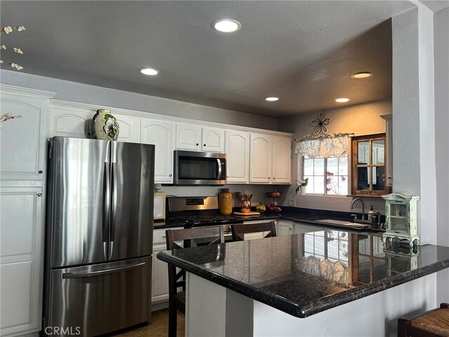 kitchen featuring sink, white cabinets, appliances with stainless steel finishes, and kitchen peninsula