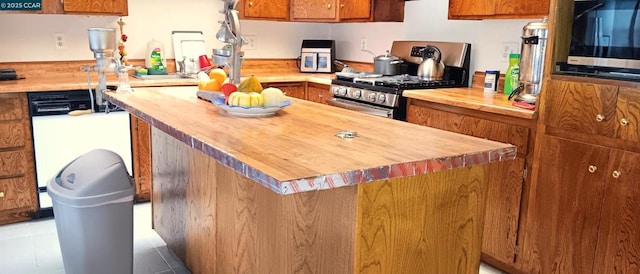 kitchen with wooden counters, light tile patterned flooring, stainless steel appliances, and a kitchen island