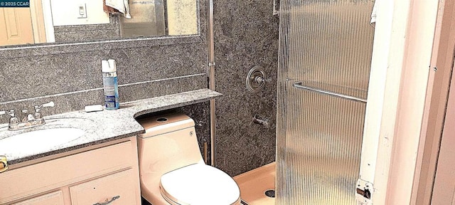 bathroom with toilet, a shower, and vanity