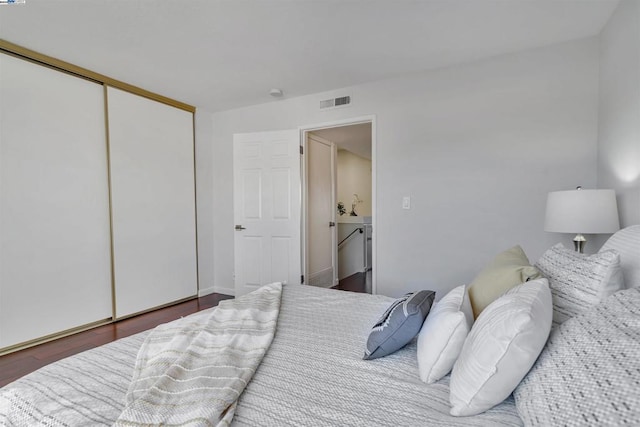 bedroom with dark hardwood / wood-style floors and a closet