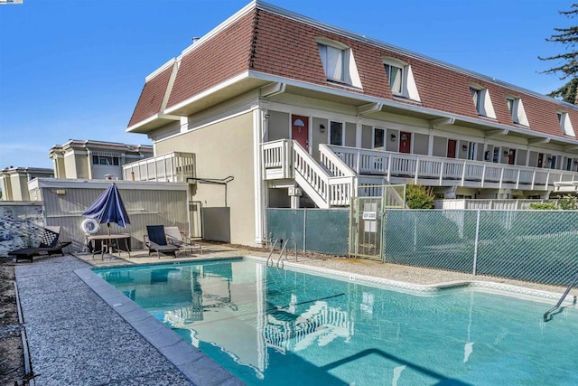 back of property featuring a patio area and a fenced in pool